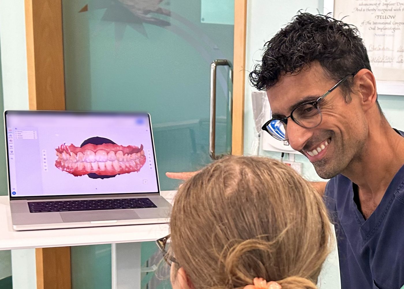 Dr Sanjay Narda talking a patient through a 3D scan of her teeth on screen